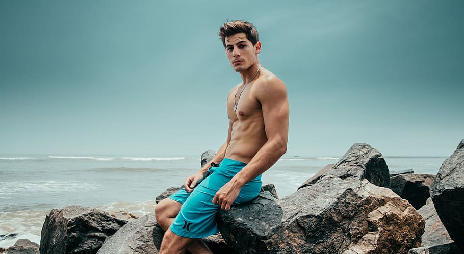 man sitting in the rock, man sitting on rock near body of water HD wallpaper