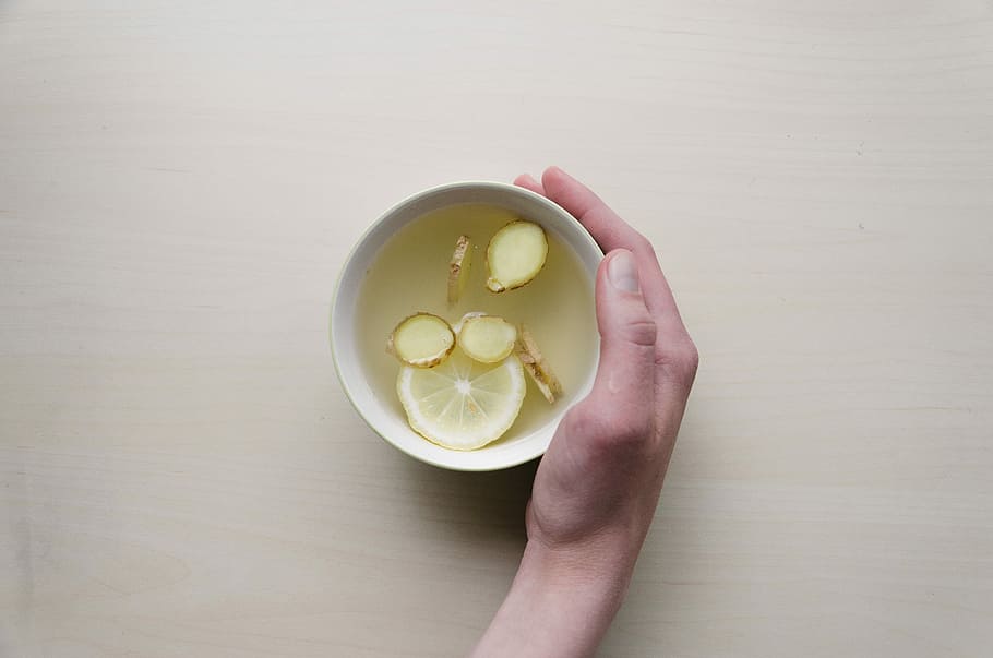 person holding white bowl with sliced lime and ginger inside, person hold white ceramic mug HD wallpaper
