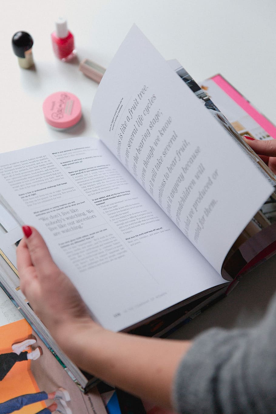 person opening the book, person reading book near nail lacquer bottle HD wallpaper