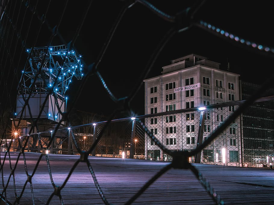 closeup photography of cyclone fence, lighted-up white concrete building HD wallpaper