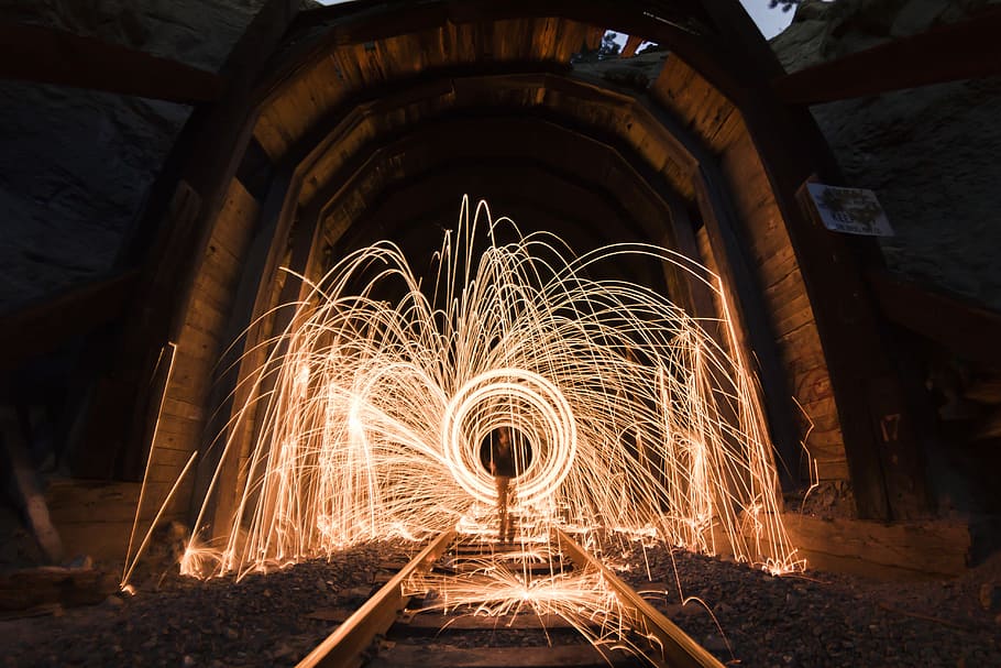steel photography of light inside arch, timelapse photography of person between ring of fire in train railway