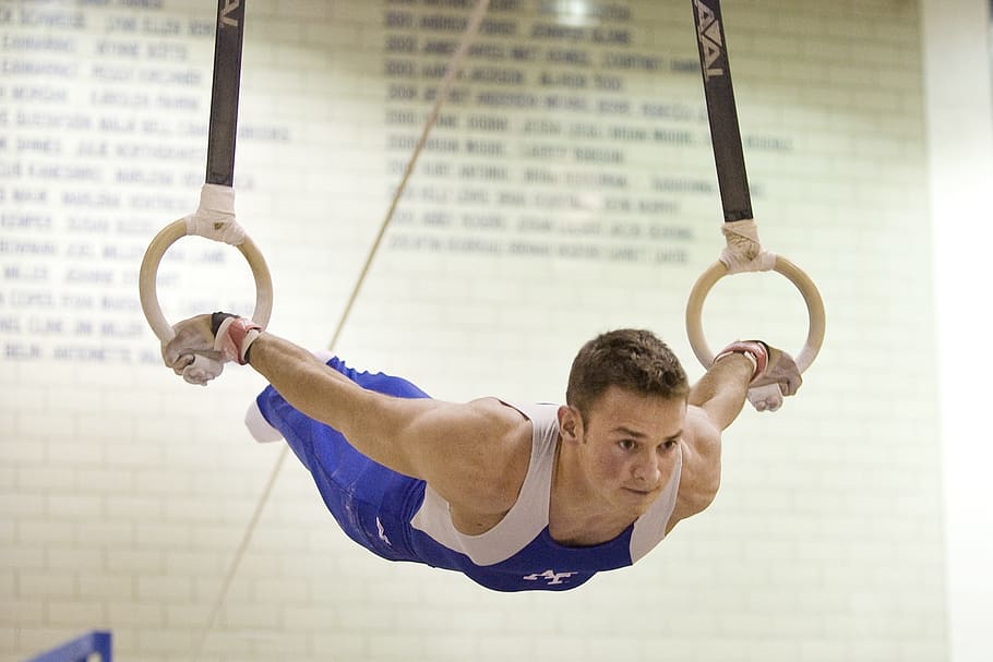 person wearing blue and white overall, rings, athlete, gymnastics