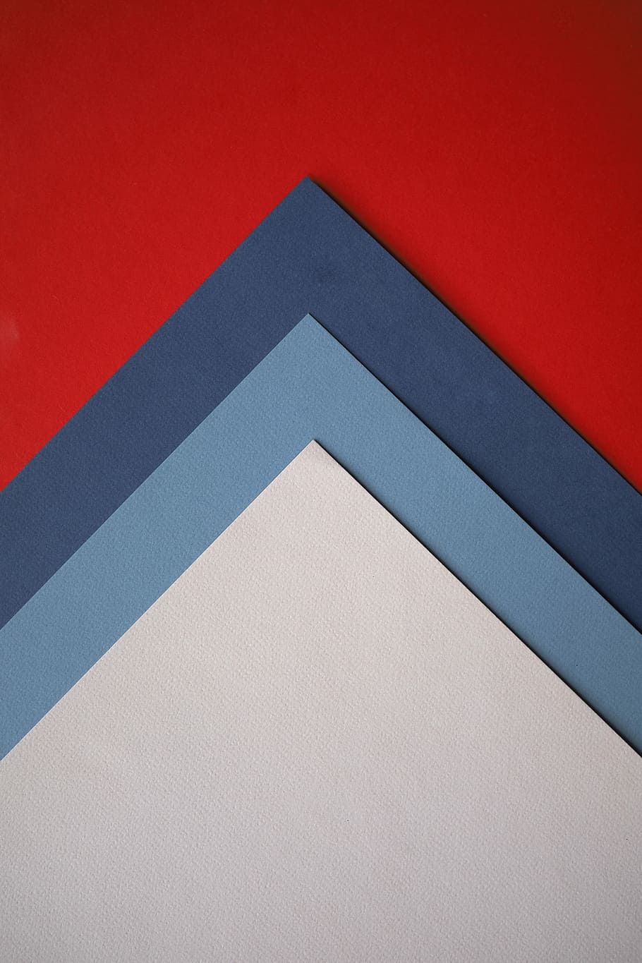 three white, blue, and black papers on red surface, color, triangle