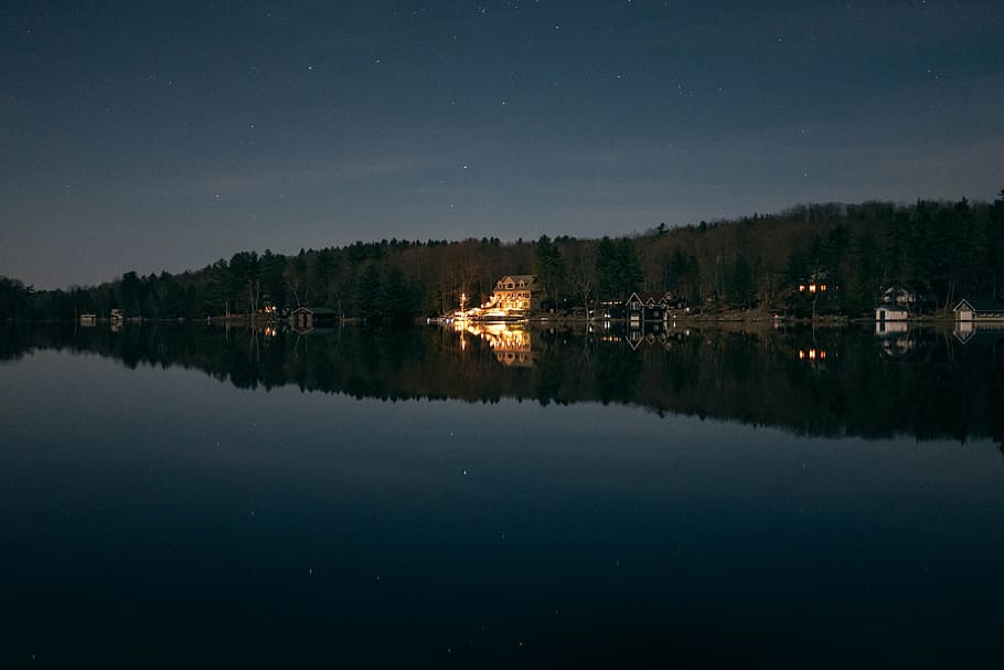lighted beige house beside shoreline during nighttime, green trees near body of water HD wallpaper