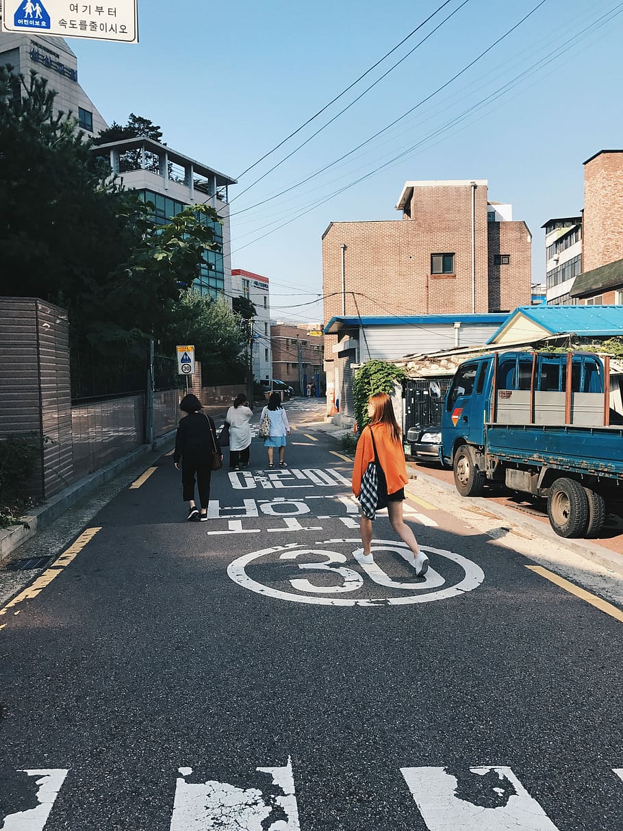 Sunny morning in Seoul, four women walking on street between establishments