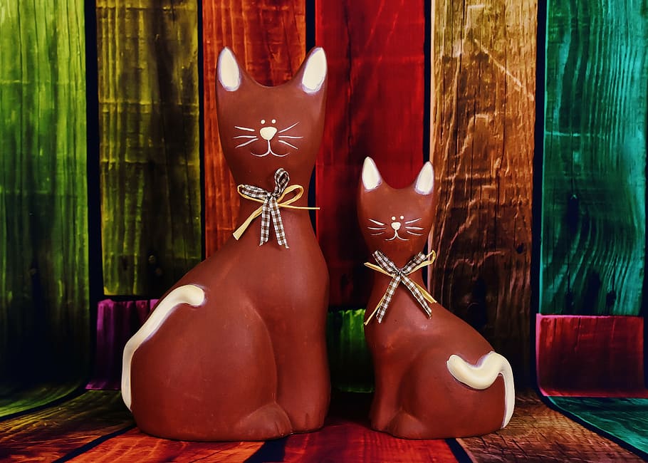 two brown ceramic cat figurines on multicolored wooden surface HD wallpaper