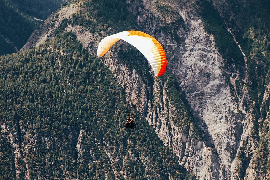 bird's eye view photography of man parachuting near mountain, white and yellow parasailing, HD wallpaper