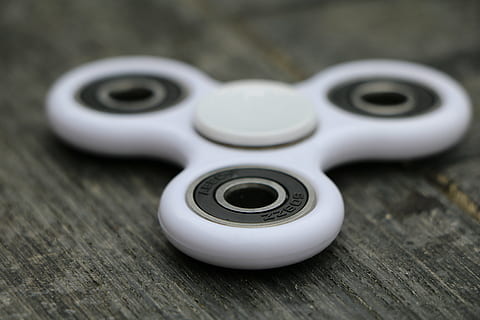 selective focus photography of white fidget spinner on brown surface HD wallpaper