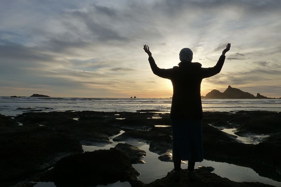 silhouette photo of person rising his hands, sunset, water, sea