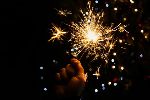 person holding sparkler with background of boke lights, effulgence HD wallpaper