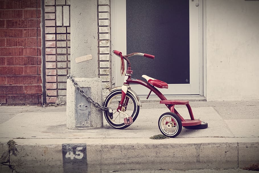 red and white bicycle chained on white post near black and white wooden closed door HD wallpaper