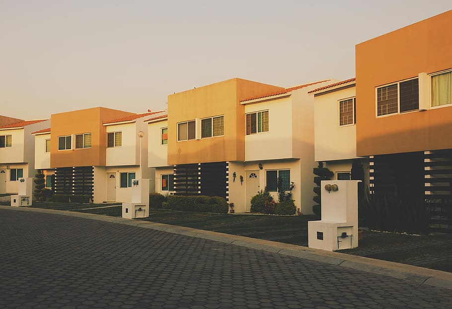 white and orange painted residential building, photo of white-and-orange concrete houses under cloudy sky HD wallpaper