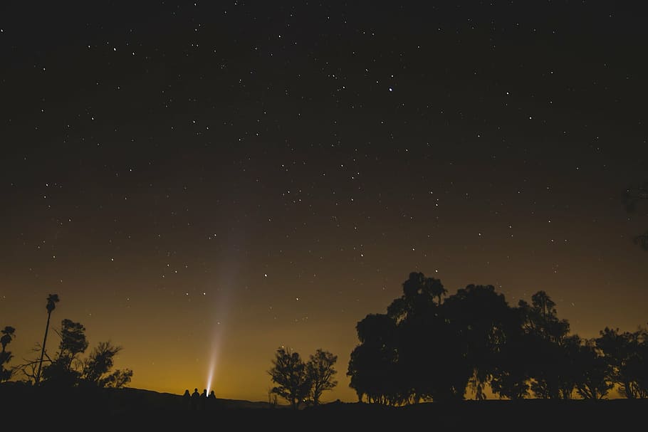 silhouette of four people lighting flashlight up in the starry sky HD wallpaper