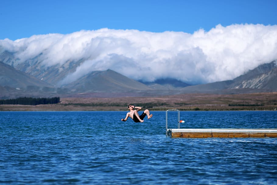 man jumps on body of water holding his nose, man jump to body of water HD wallpaper