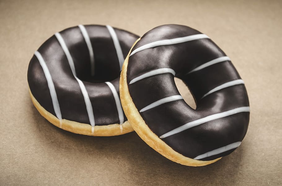 macro photography of chocolate donuts, two chocolate doughnuts on brown surface