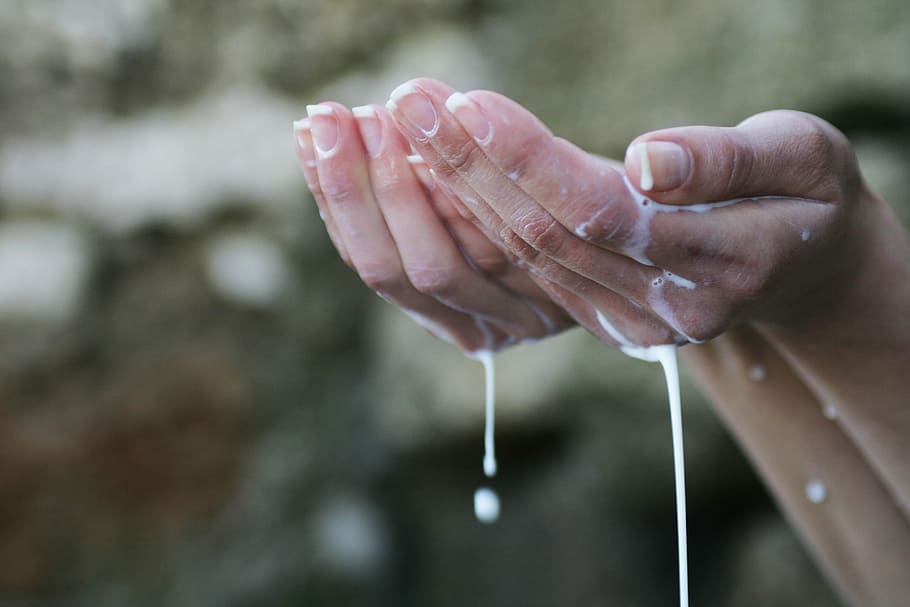 selective focus photography of person's hand holding white liquid HD wallpaper
