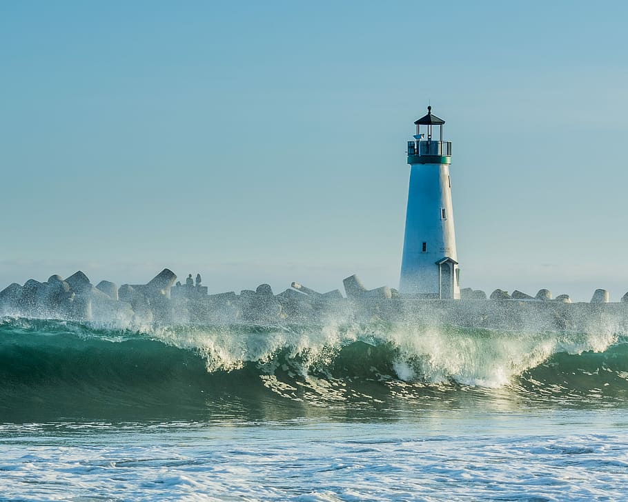 concrete lighthouse near rocks and ocean wave at daytime, lighthouse near body of water HD wallpaper