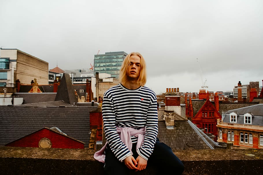 man sitting on roof top fence, man wearing striped shirt sitting on roof HD wallpaper