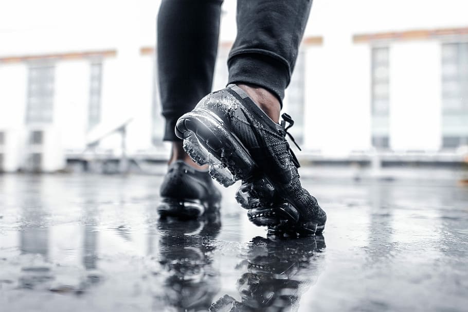 person wearing black Nike Vapormax shoes on wet floor, person wearing black Nike Air Max shoes while stepping in water