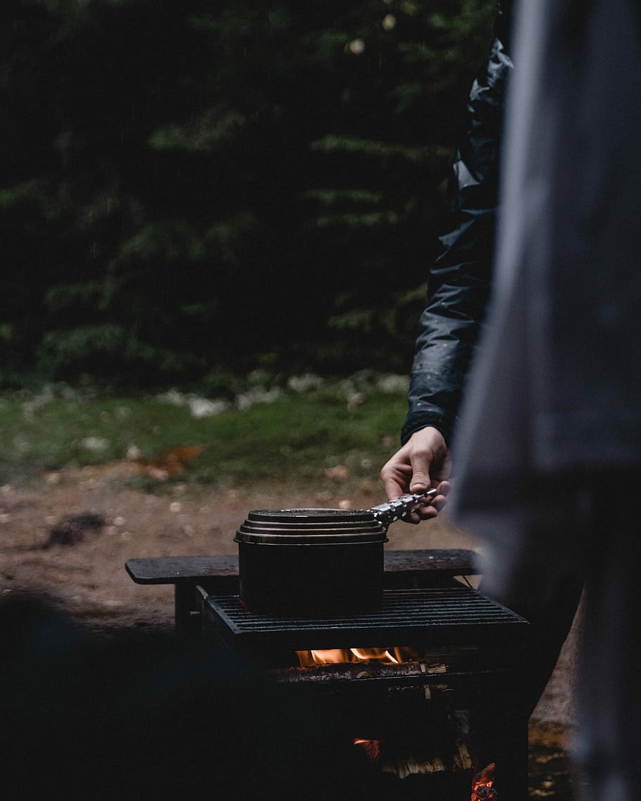 person standing beside black firepit, person in black jacket cooking on charcoal grill HD wallpaper
