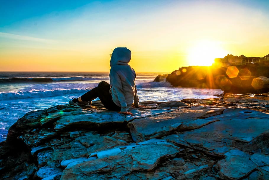 person wearing hoodie sitting on stone, sunset, santa cruz, water, HD wallpaper