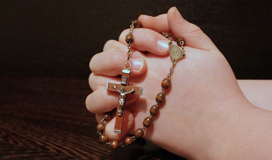 person holding brown rosary necklace, faith, pray, folded hands