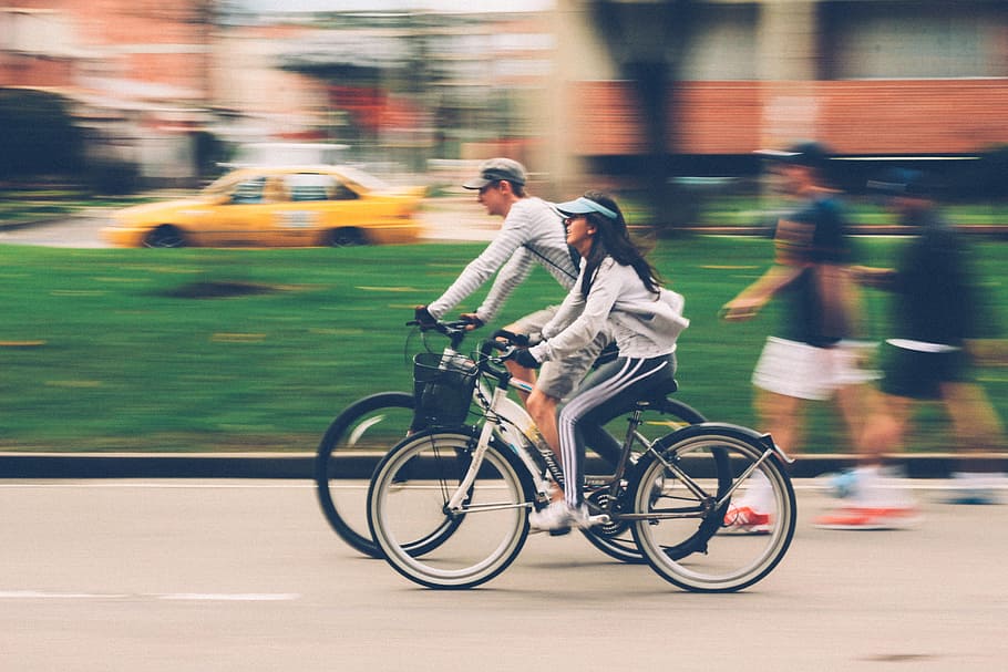 woman riding white road bike beside man riding black bike, people