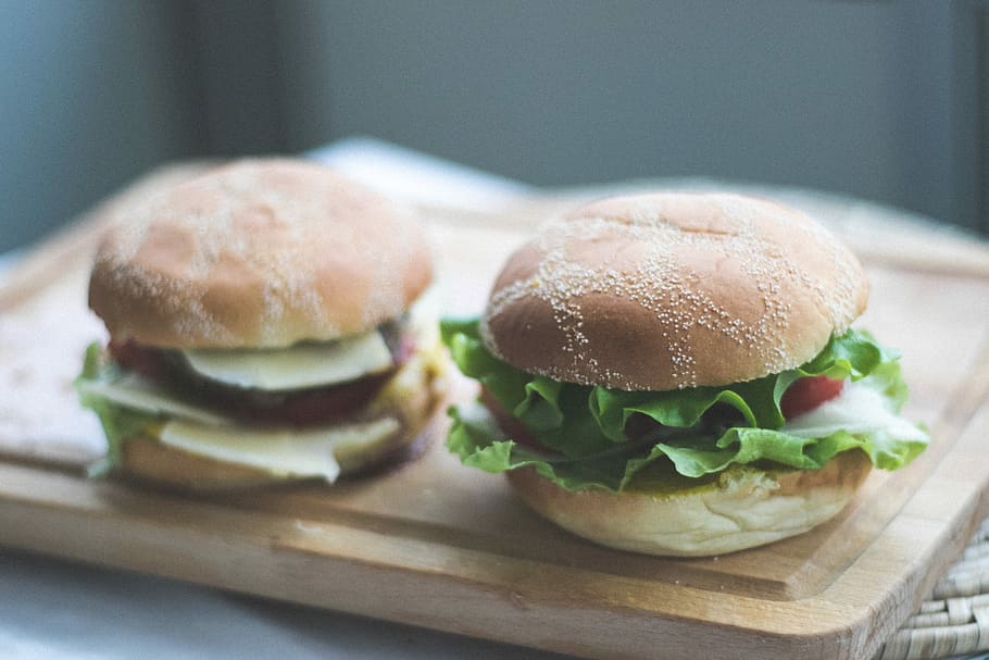 two burgers on brown wooden chopping board, two hamburgers on brown wooden tray HD wallpaper
