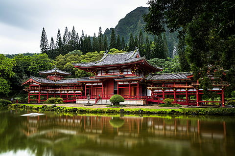 red castle near calm water behind mountain at daytime, red and black mansion near body of water HD wallpaper