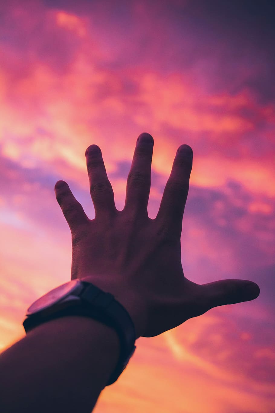 person with black watch reaching for orange sky, person hold under golden hour HD wallpaper