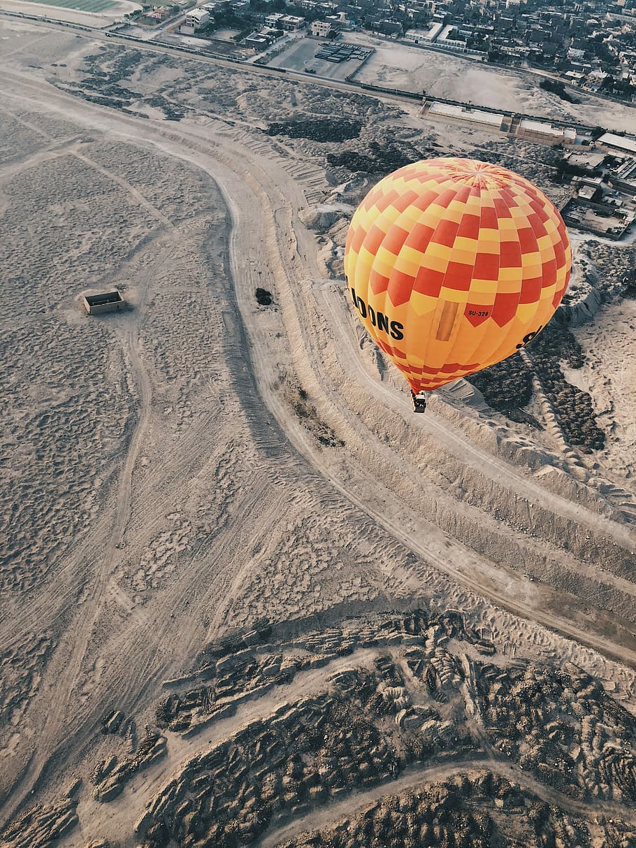 aerial photography of hot air balloon floating on air, red and yellow hot air balloon flying over city HD wallpaper