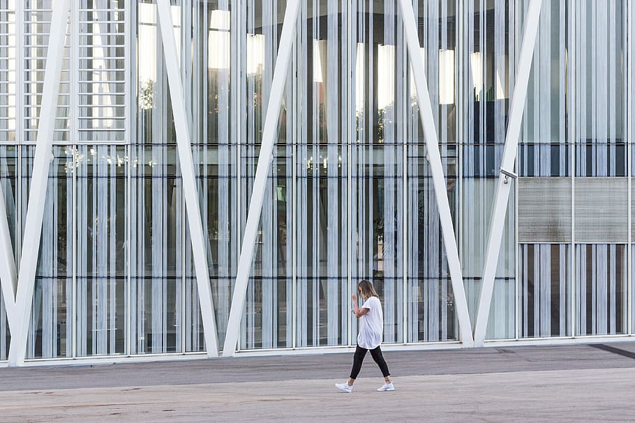 woman walking beside white painted building taken at daytime, woman walking on street beside glass building HD wallpaper