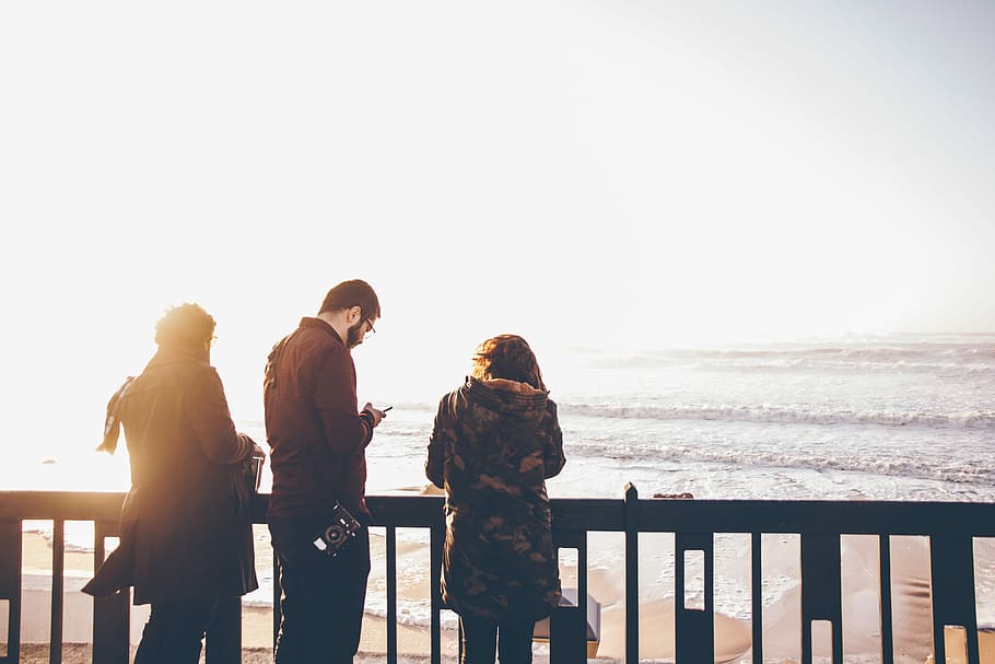 three people standing in front of beach, man and woman near fence HD wallpaper