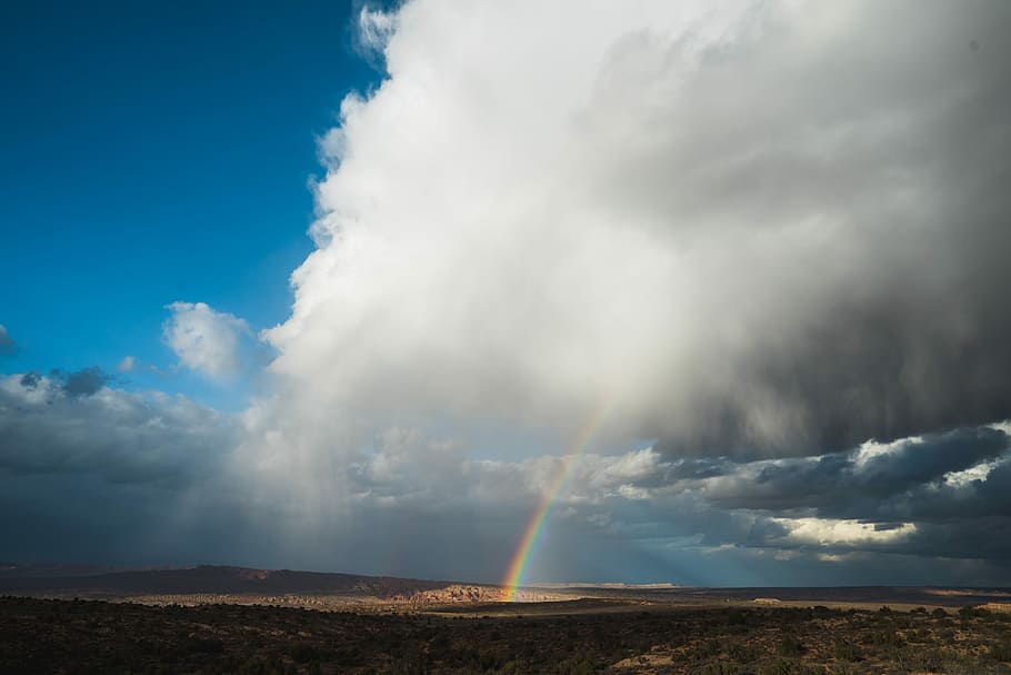 rainbow under cloudy skies, gray clouds with rainbow above the field HD wallpaper