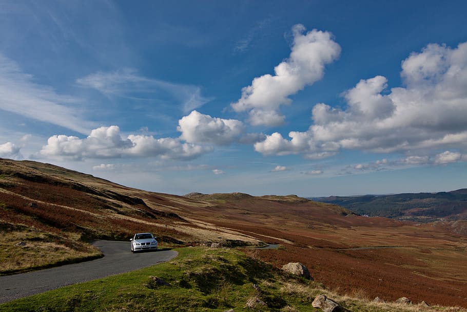 A BMW car drives along an open and twisting road in the Lake District in Cumbria, England HD wallpaper