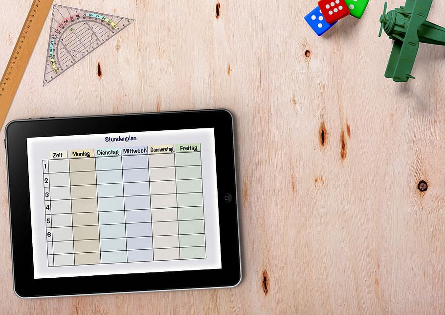 rectangular black Android tablet computer on brown surface, timetable