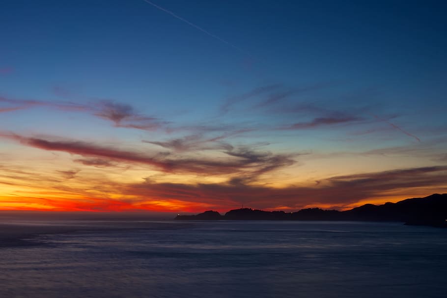 sunset over the horizon, silhouette of island during golden hour HD wallpaper
