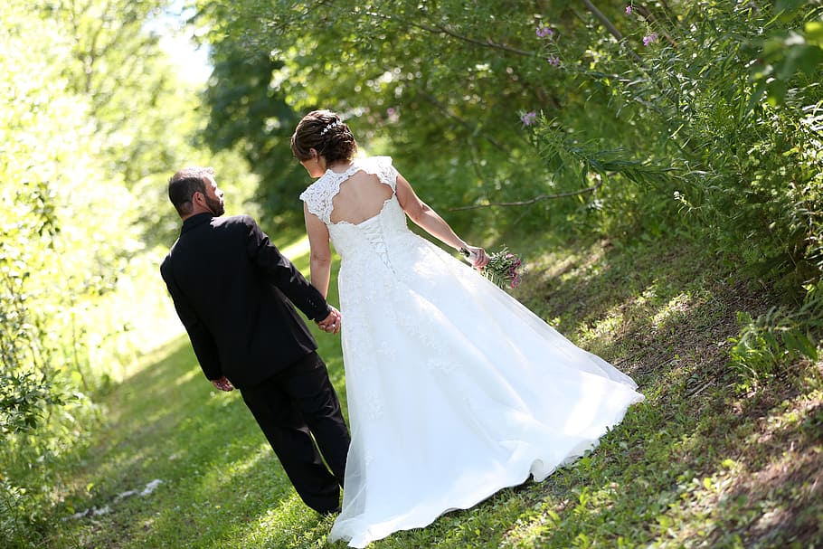 couple walking on green road during daytime, wedding, bride, groom