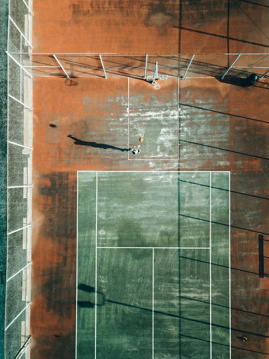 tennis court and basketball court top view, top view photography of man playing basket on court during daytime