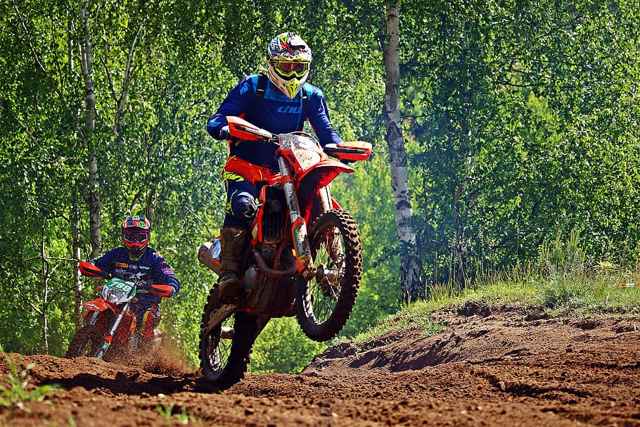 two riders racing at motocross field surrounded by trees during daytime HD wallpaper