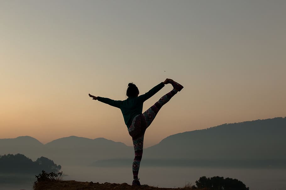 person doing stretching during golden hour, silhouette, yoga