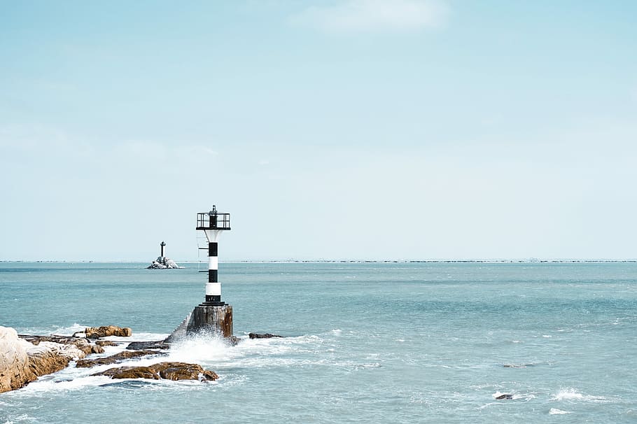 photography of white and black lighthouse, white and black lighthouse between rock and sea at daytime HD wallpaper