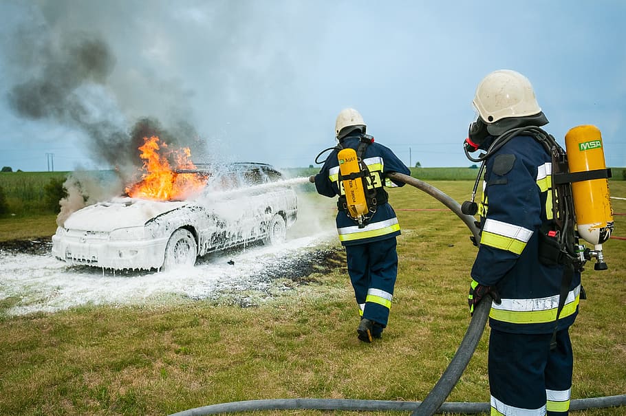 two firefighters fighting fire on grey station wagon on field during daytime HD wallpaper