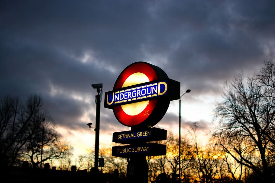 lighted yellow and red Underground signage under grey cloudy sky, Underground signage with light HD wallpaper