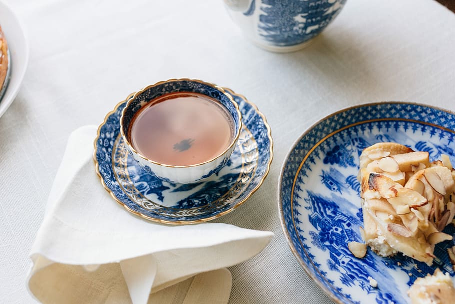 cup filled with brown liquid near plate, blue and white ceramic teacup on top of plate HD wallpaper