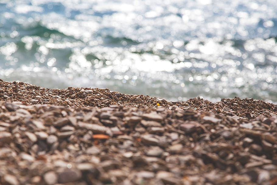 stones beside body of water during daytime, photo of brown sand near sea at daytime HD wallpaper
