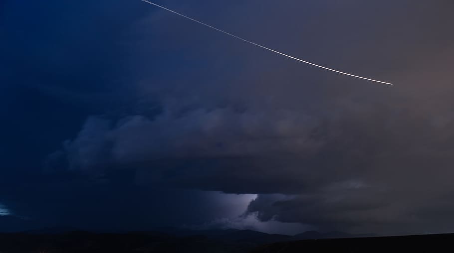 jet flying on sky with dark clouds, aerobatic plane in the sky with white smoke trail HD wallpaper
