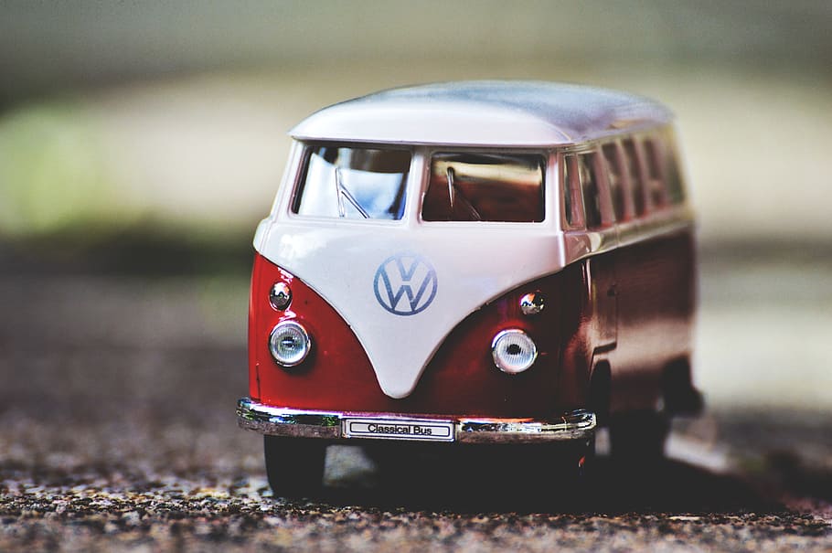 white and red Volkswagen T1 scale model on gray dirt selective focus photography