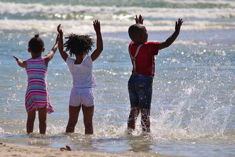 three kids playing on grey body of water during daytime, children