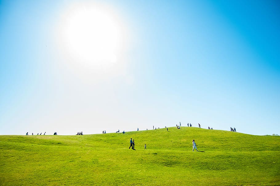 group of people on green field, people walking around a green grass hill HD wallpaper